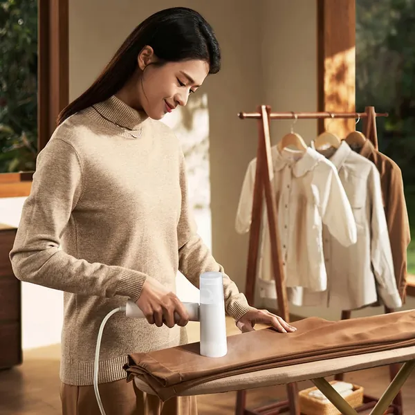 Woman steaming a shirt with the MIJIA handheld steamer